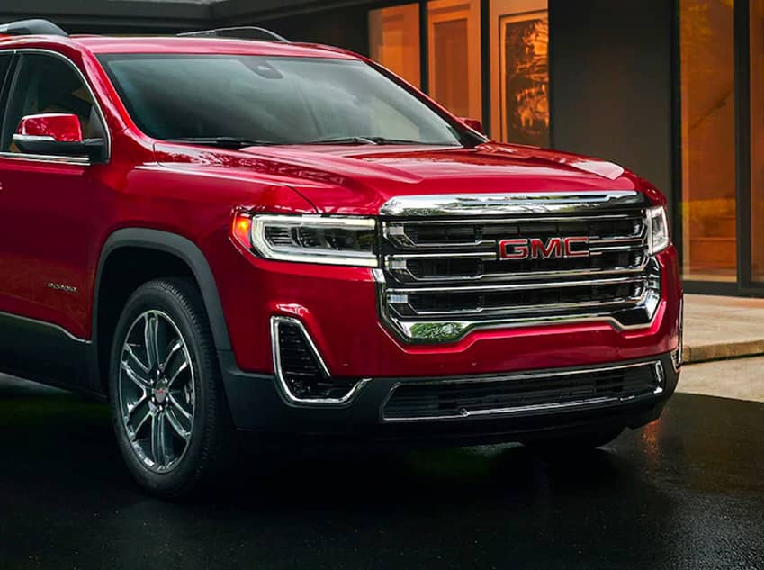 A side facing red Acadia parked on a street