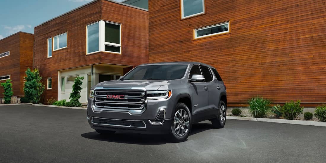 A silver Acadia parked in front of a building