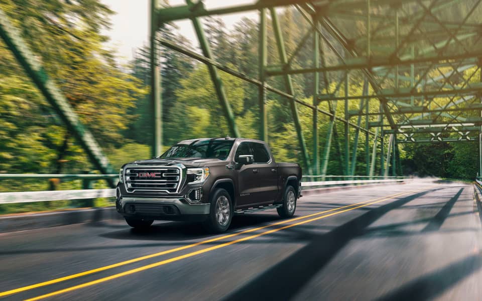 Brown GMC Sierra 1500 crossing over a steel bridge