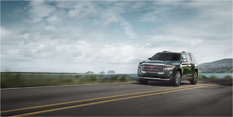 2023 GMC Acadia driving near a lake shore